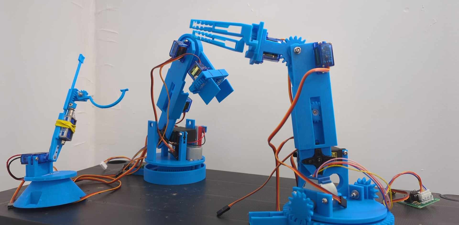 Three blue 3D-printed Desk Buddy robot arms, showing the project evolving from an early prototype into a robotic companion